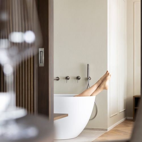 Füße ragen aus einer freistehenden Badewanne in einer eleganten Hotelsuite