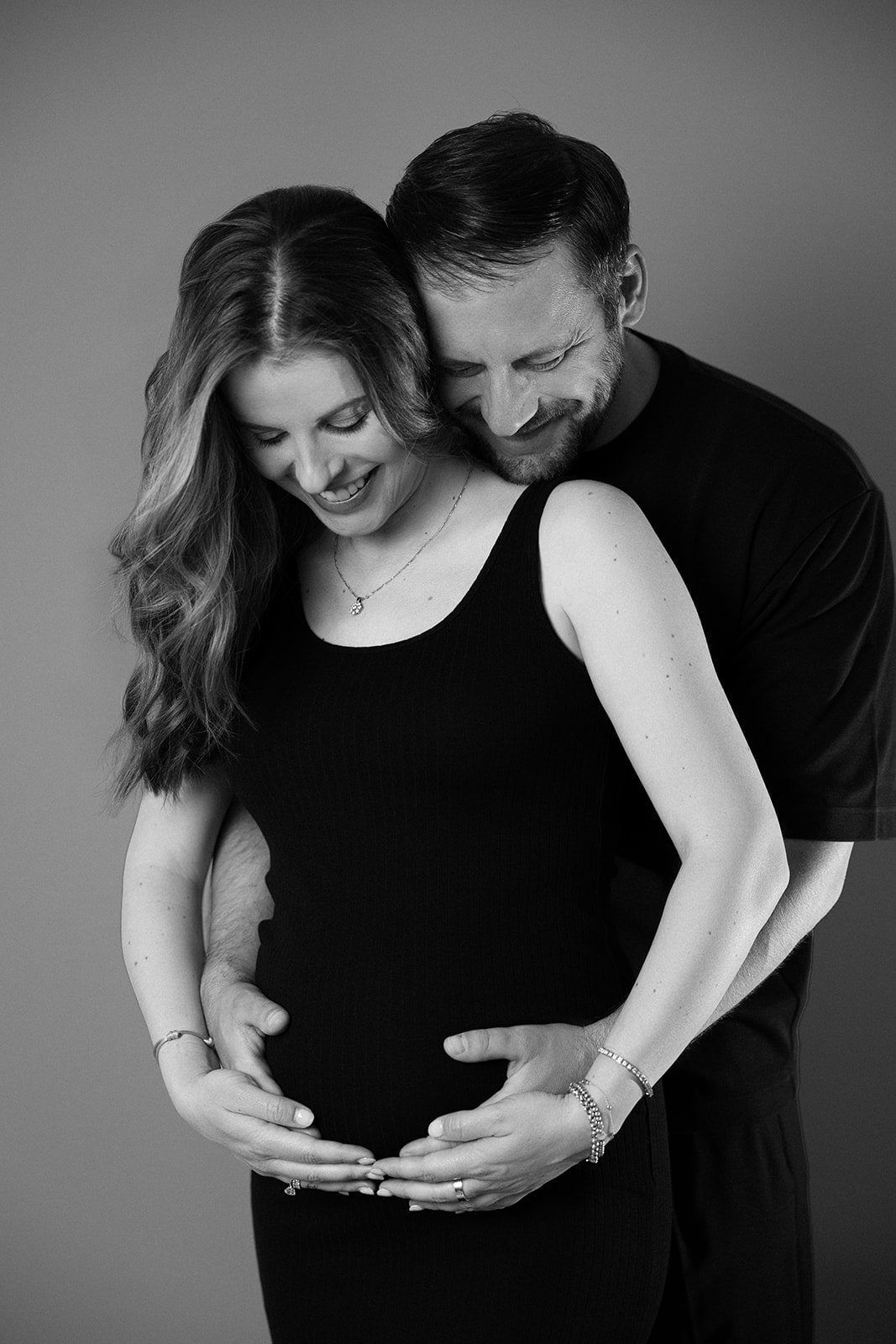 Werdende Eltern, Hände am Babybauch, Schwarzweiß